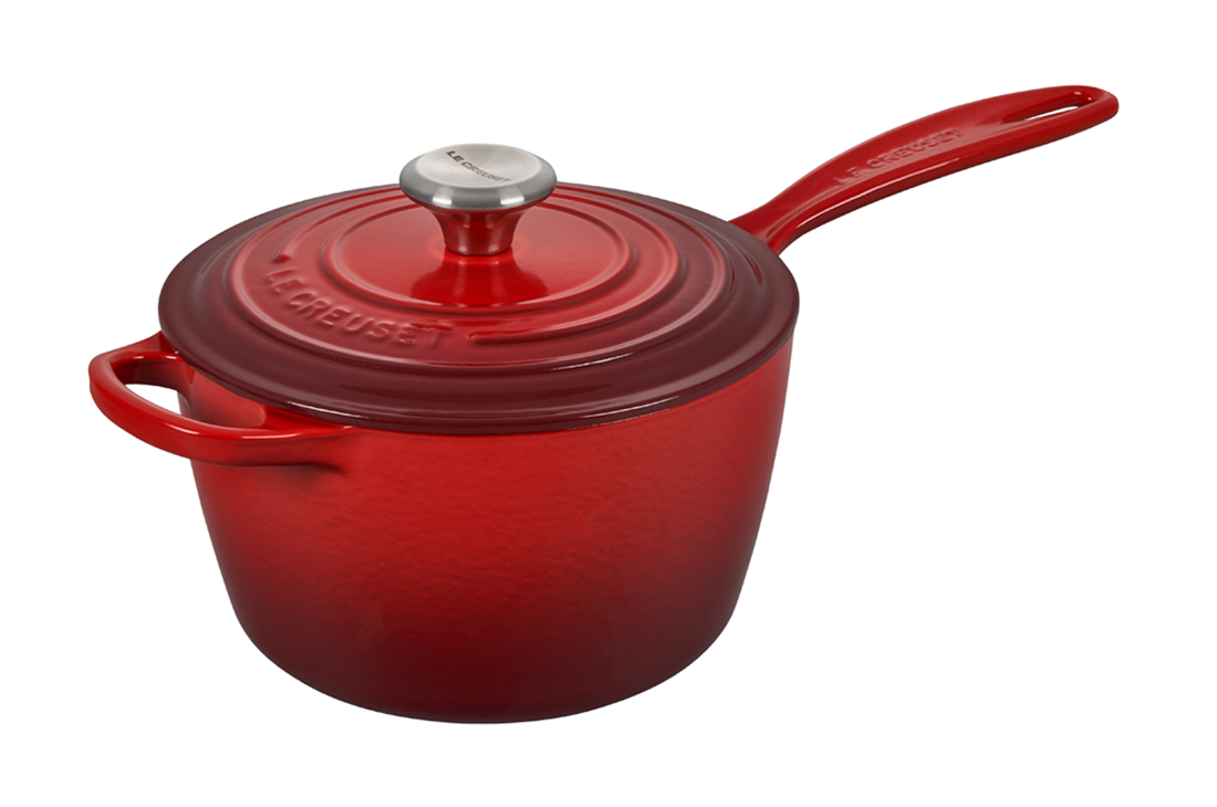 Red enameled cast iron saucepan with lid on white background