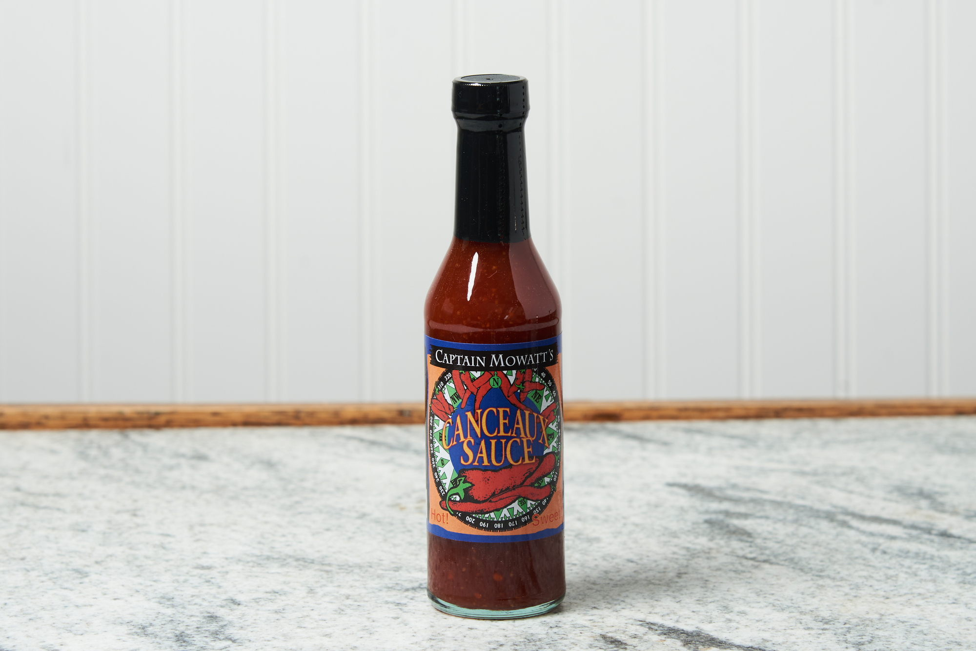 A bottle of Captain Mowatt's Canceaux Sauce sits on a marble countertop.