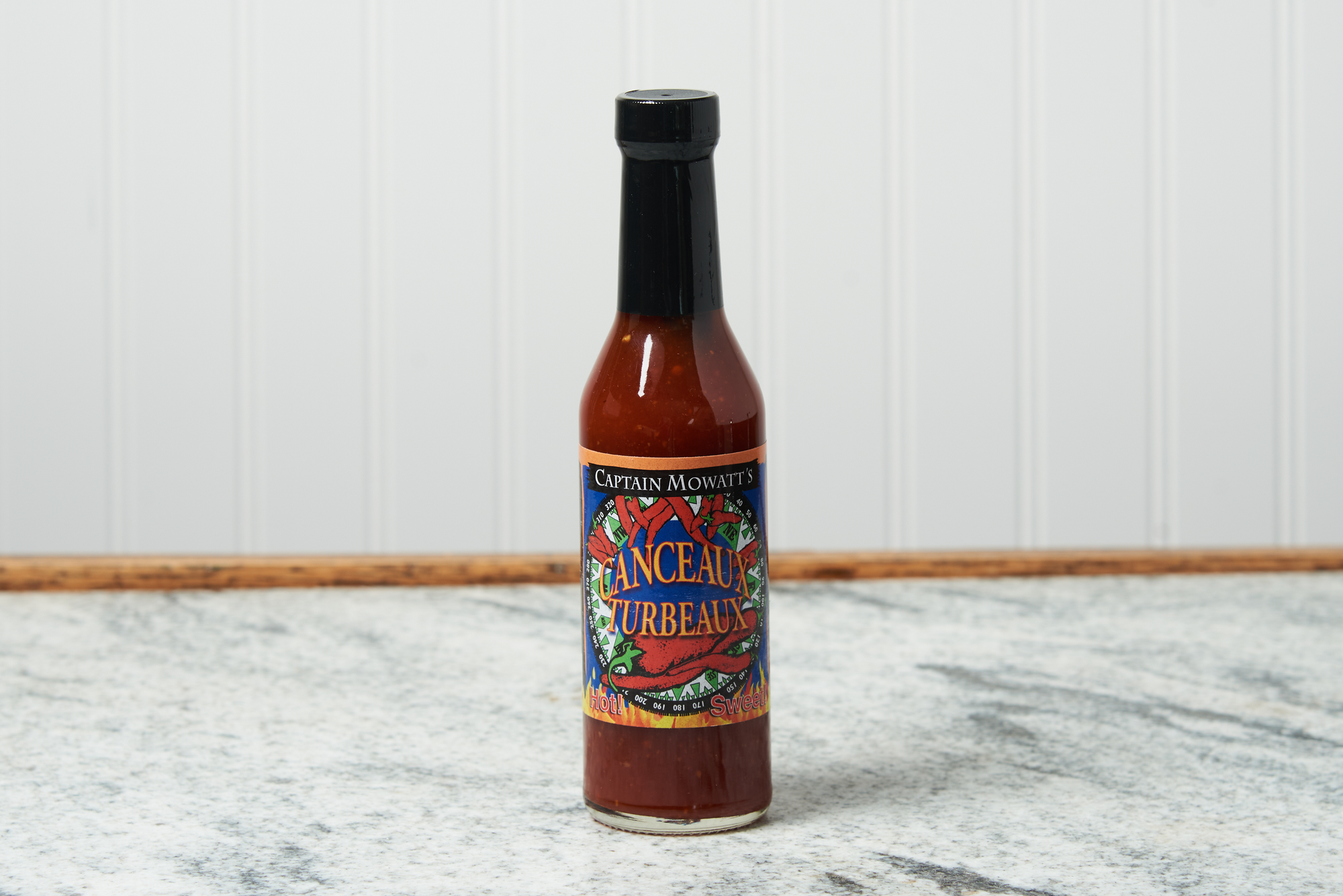 A bottle of Captain Mowatt's Canceaux Turbeaux Sauce sits on a marble countertop.