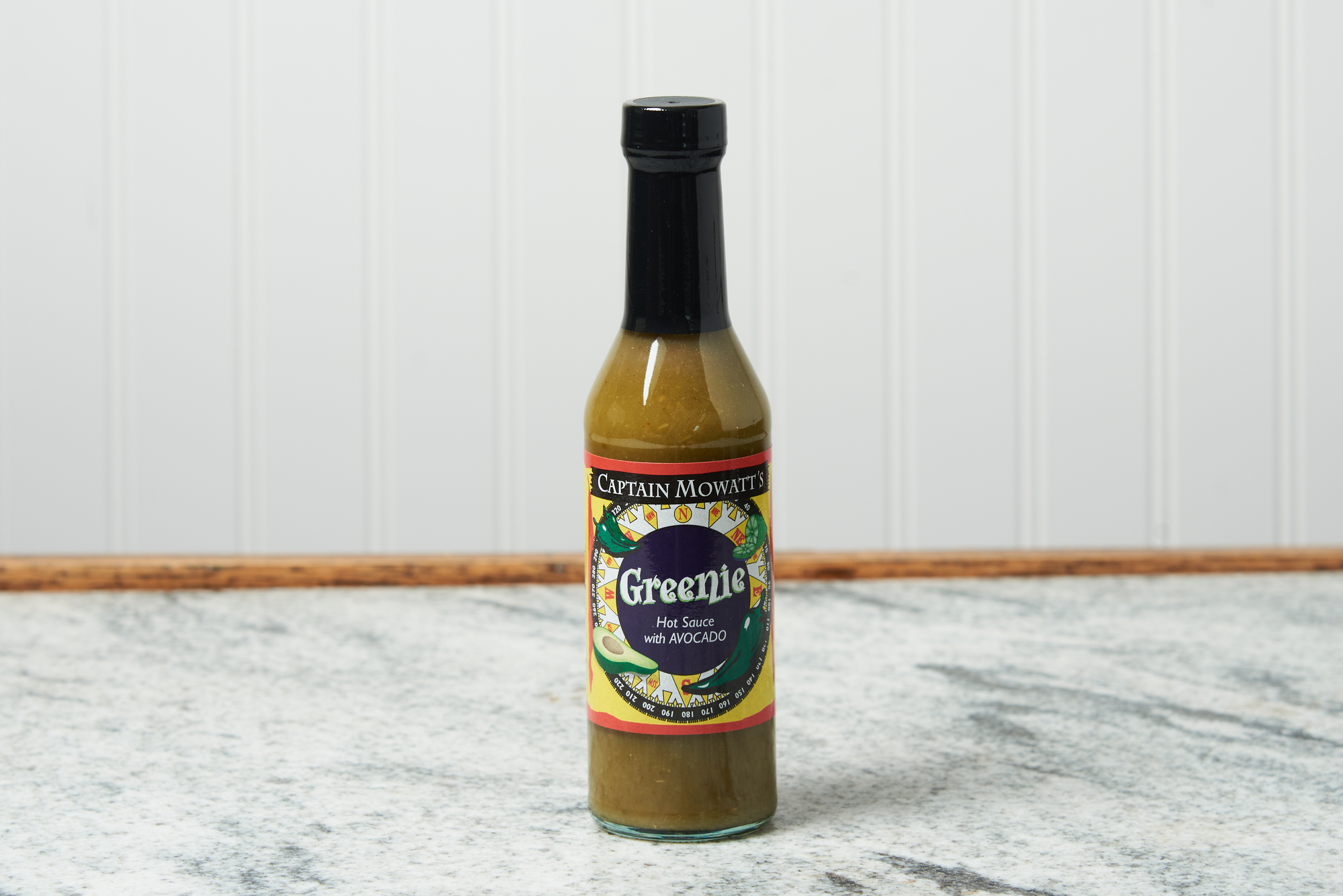 A bottle of Captain Mowatt's Greenie Sauce sits on a marble countertop.