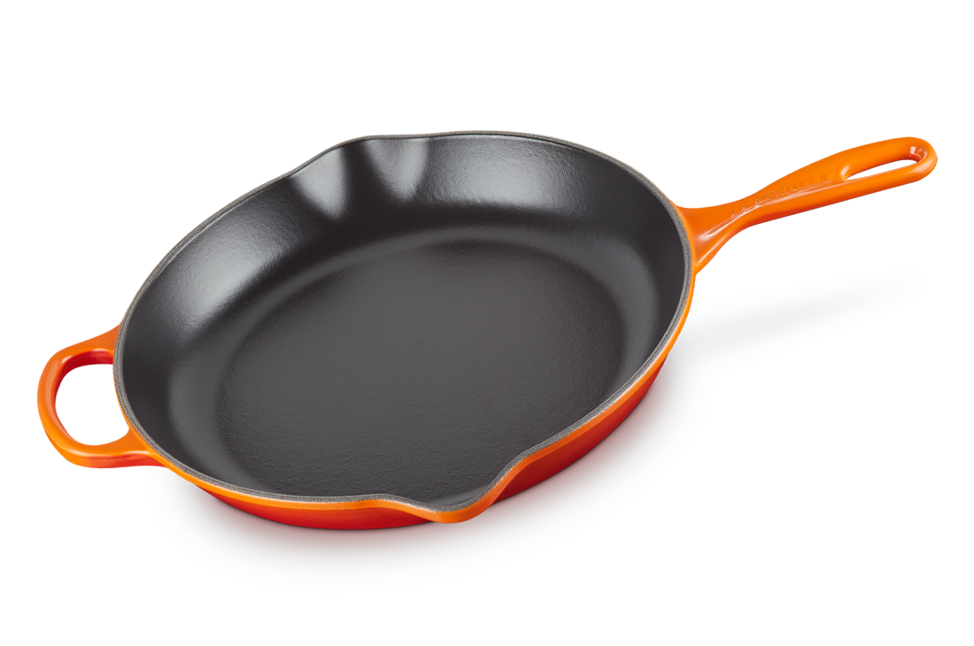 A Le Creuset 11.75 inch Signature Skillet in Flame orange over a white background.