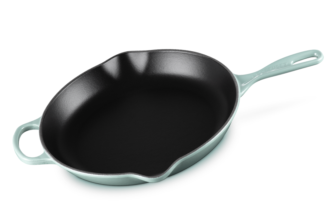 A Le Creuset 11.75 inch Signature Skillet in Sea Salt blue/green over a white background.