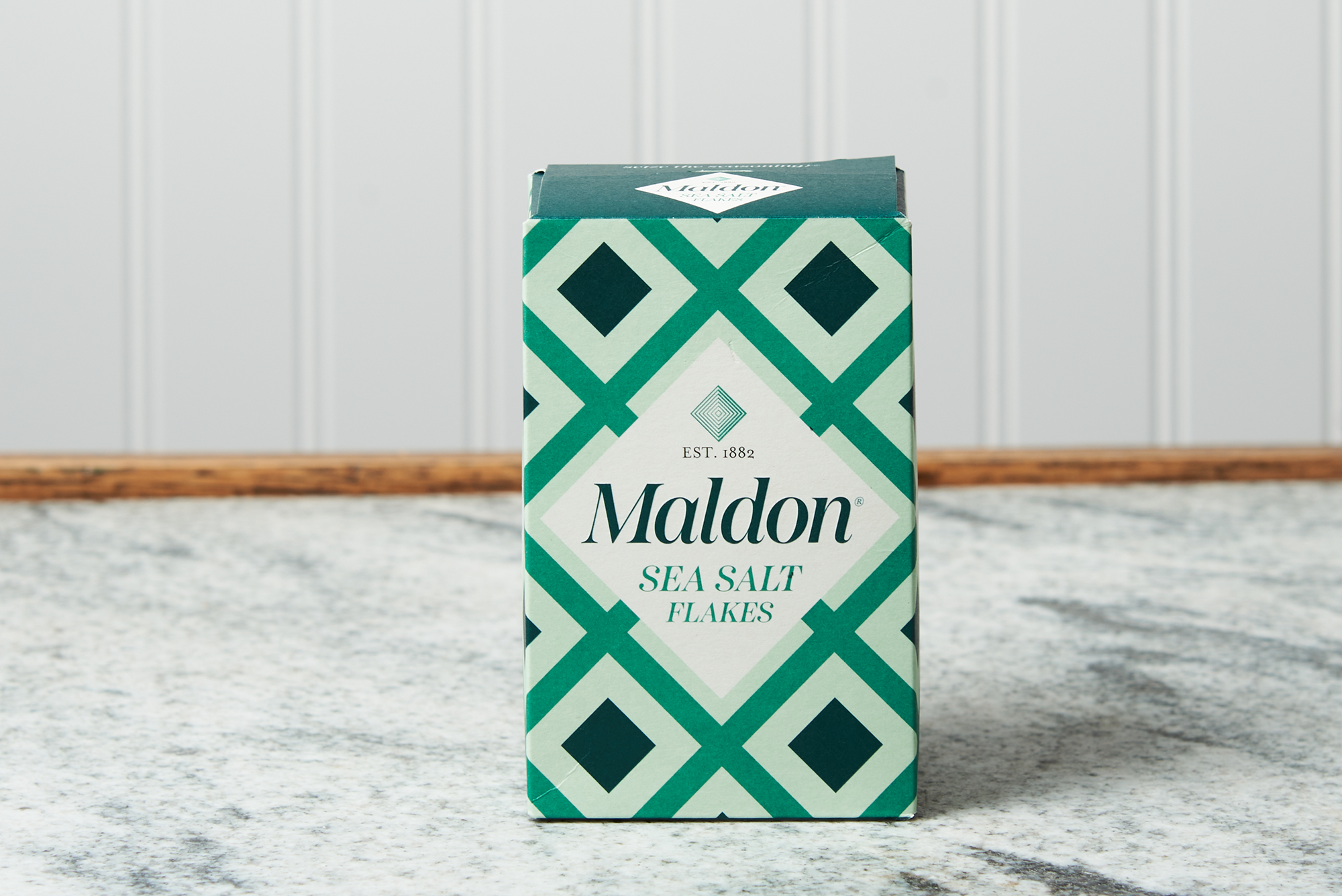 A box of Maldon Sea Salt Flakes sits on a marble countertop.