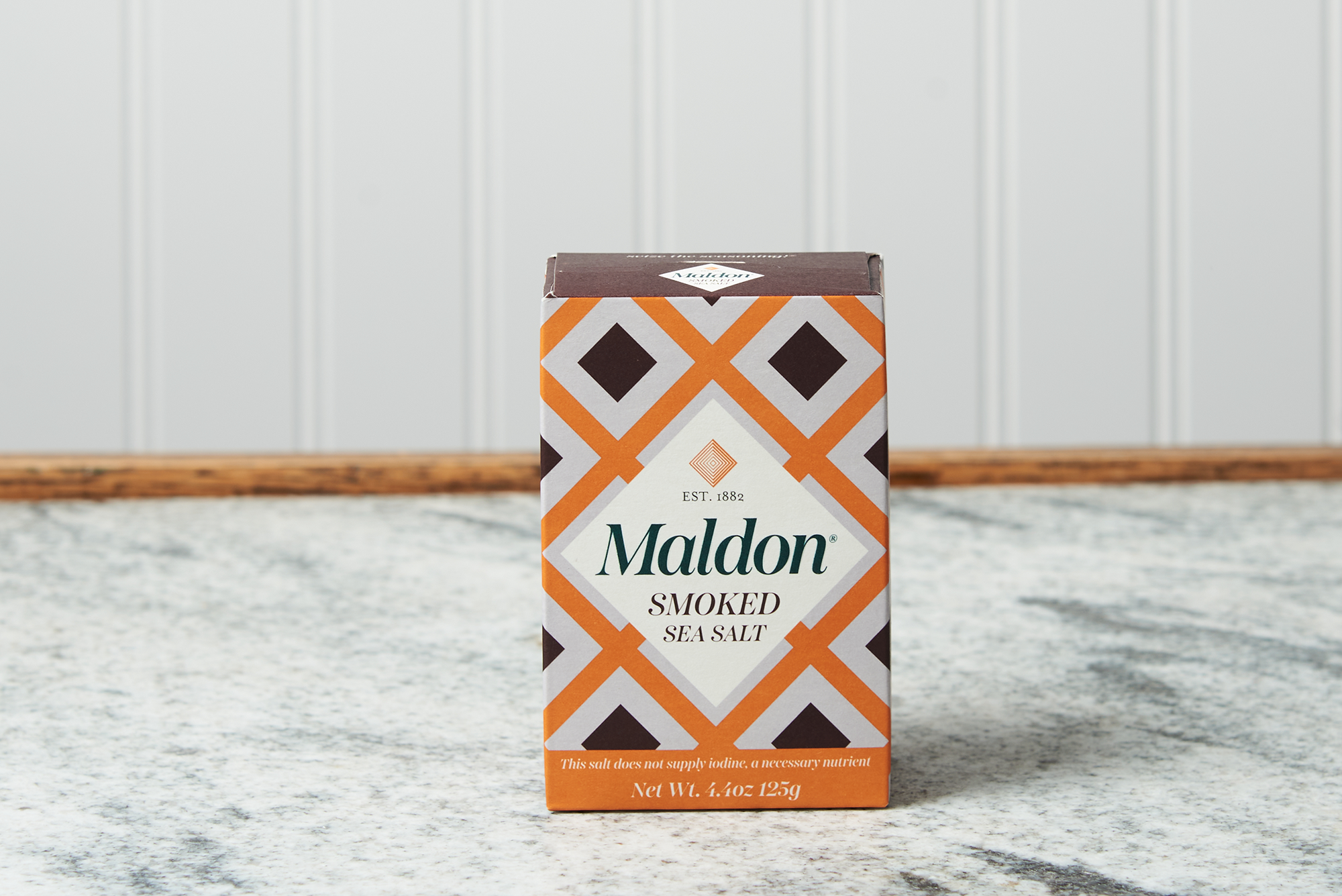 A box of Maldon Smoked Sea Salt Flakes sits on a marble countertop.