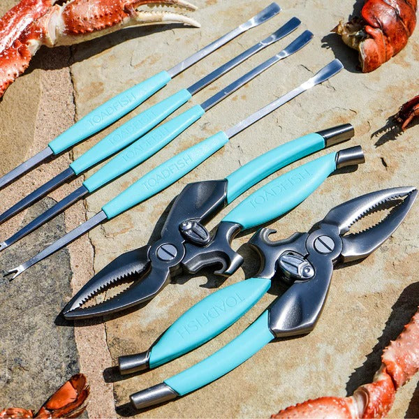 The Toadfish Crab & Lobster Tool Set sits on a rock, surrounded by crab claws.