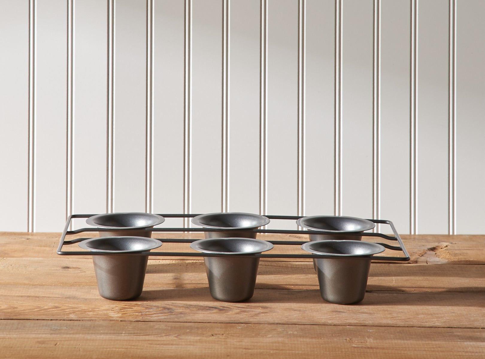 Six muffin cups in a tray on wooden surface with striped background