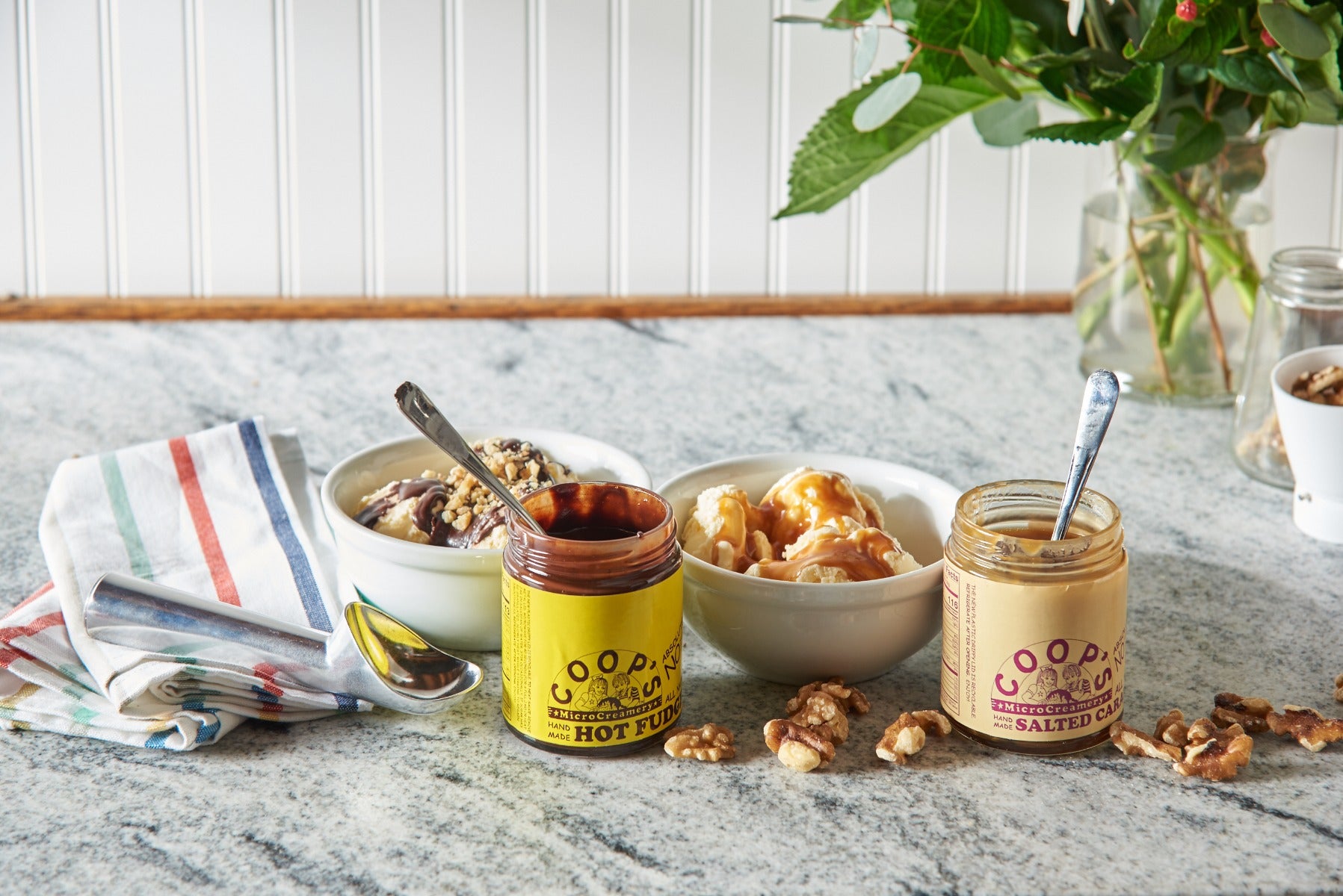 Gourmet ice cream bowls with caramel sauce and fudge on marble countertop