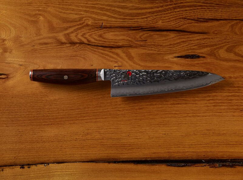 Damascus steel chef's knife with a wooden handle on a rustic wooden background