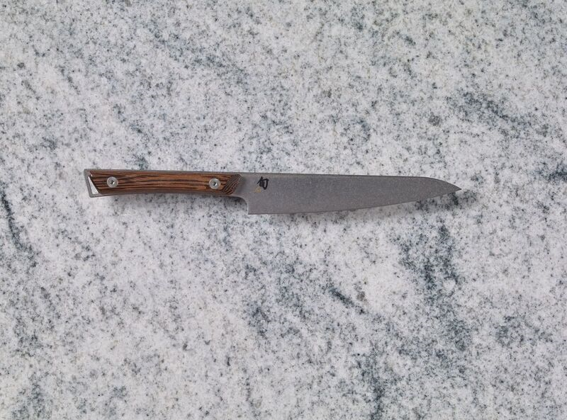 A Shun Kanso 6" Utility Knife on a marble countertop.
