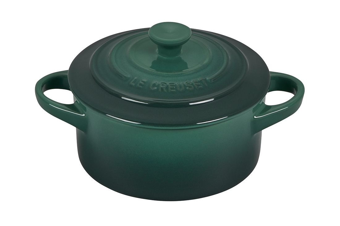 Green Le Creuset cast iron pot with lid on white background