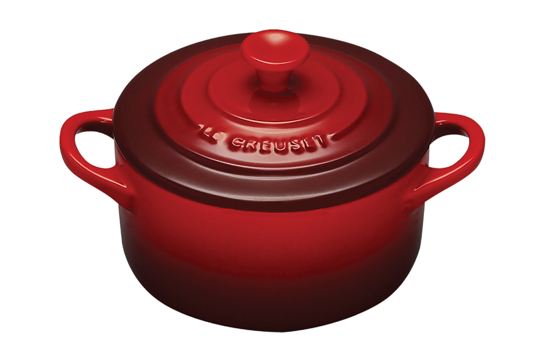 Red enameled cast iron Dutch oven by Le Creuset on a white background