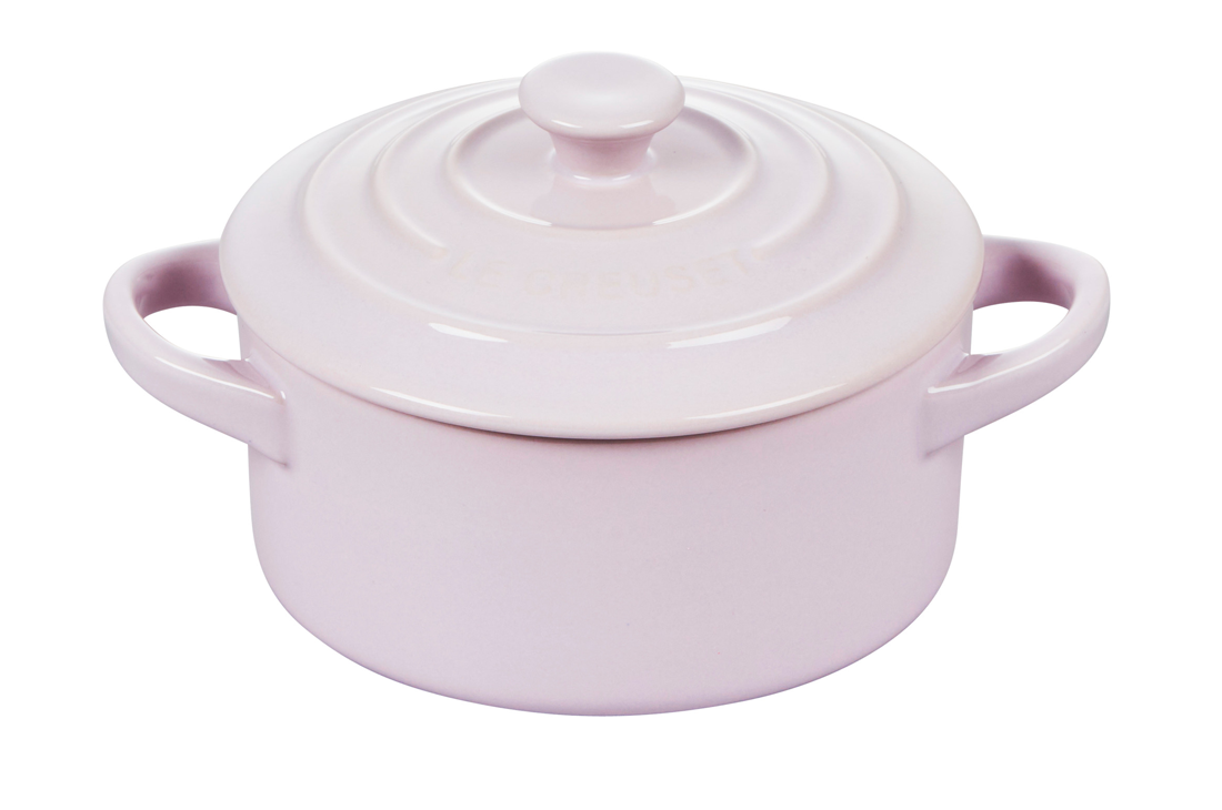 Pastel pink Le Creuset stoneware pot with lid on white background.