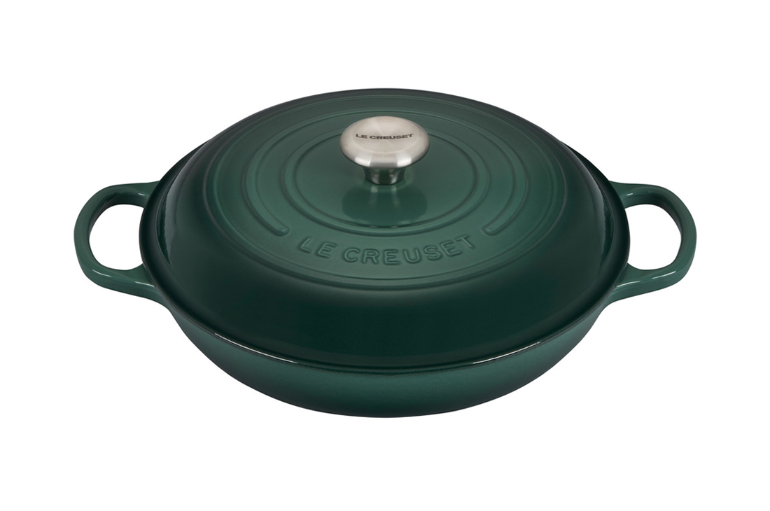 Green Le Creuset cast iron casserole dish with lid on white background