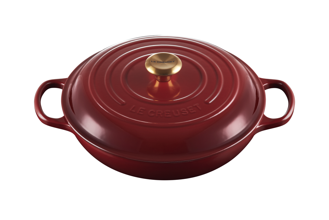 Red Le Creuset cast iron Dutch oven with gold knob on white background