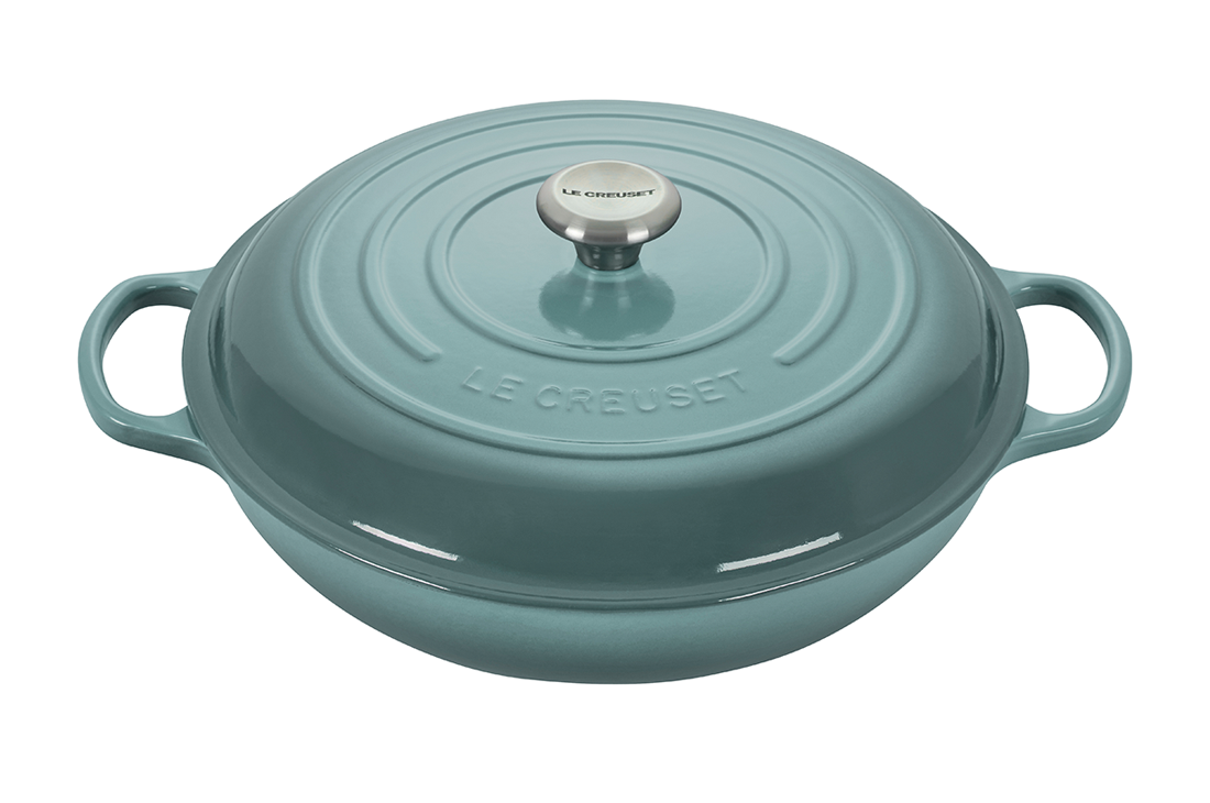 Green Le Creuset cast iron dutch oven on a white background