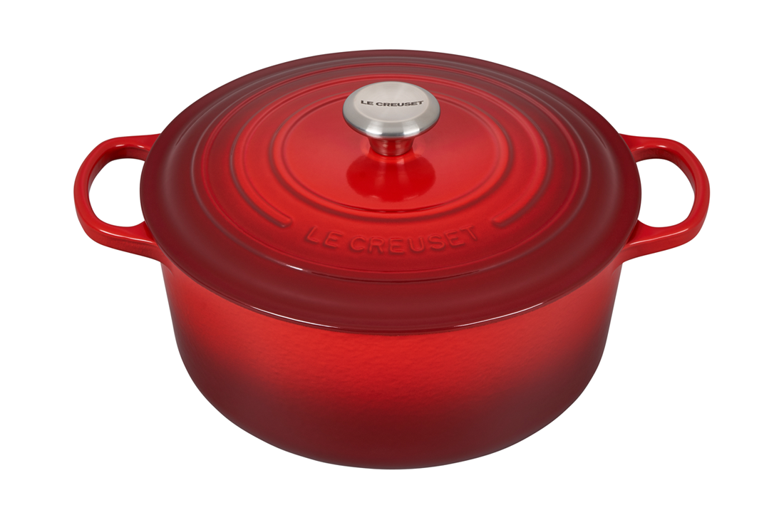Red enameled cast iron Dutch oven by Le Creuset on white background
