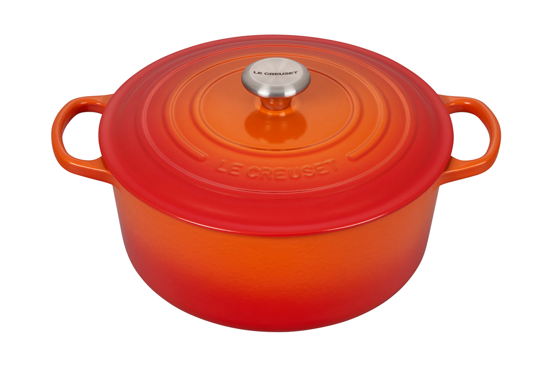 Orange enameled cast iron Dutch oven by Le Creuset on white background