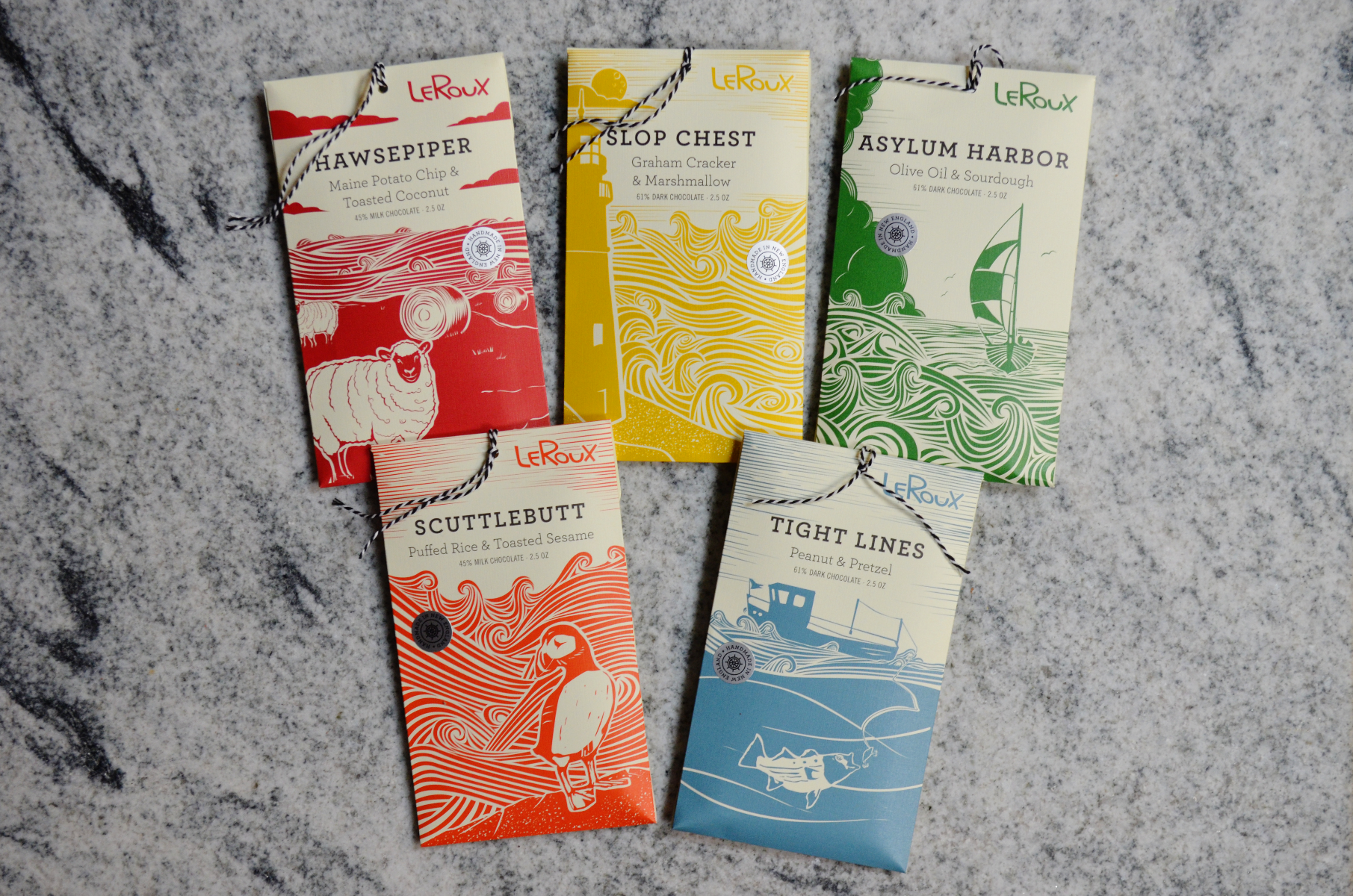 Assorted LeRoux chocolate bars with unique flavors on marble surface