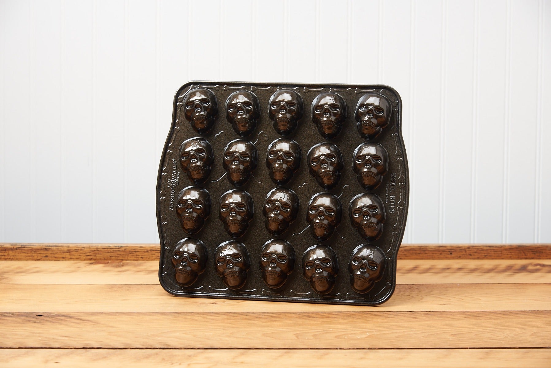 Vintage face-shaped chocolate mold on wooden surface against white wall