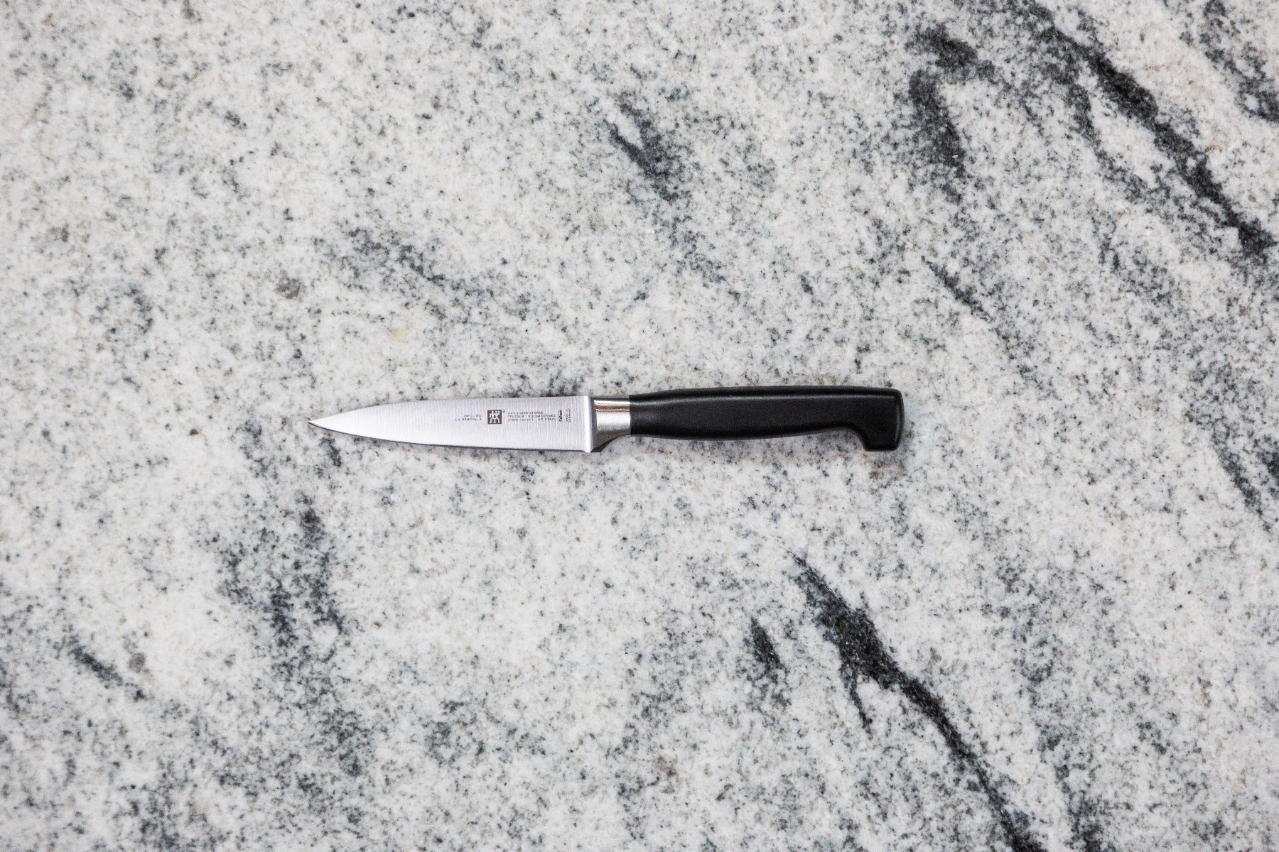 Stainless steel paring knife on a speckled marble background
