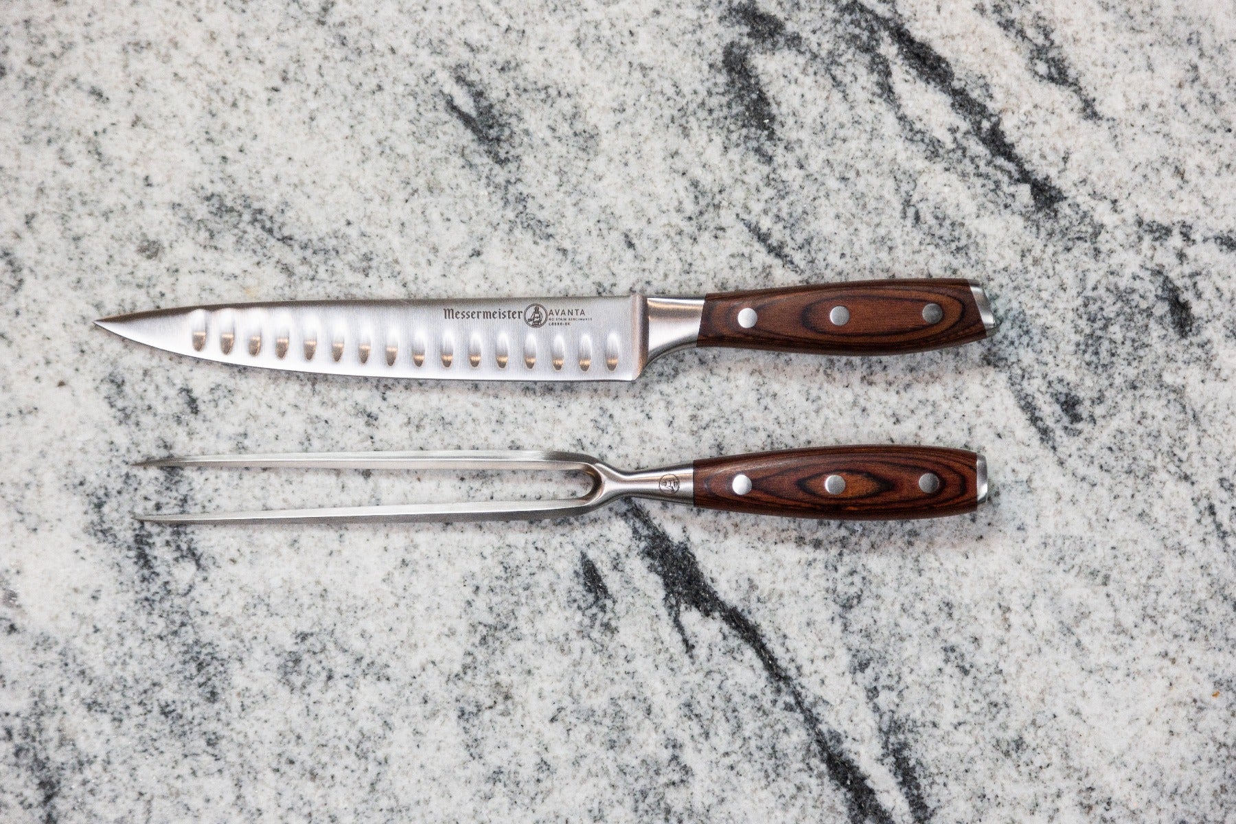 Stainless steel carving knife and fork set on marble background