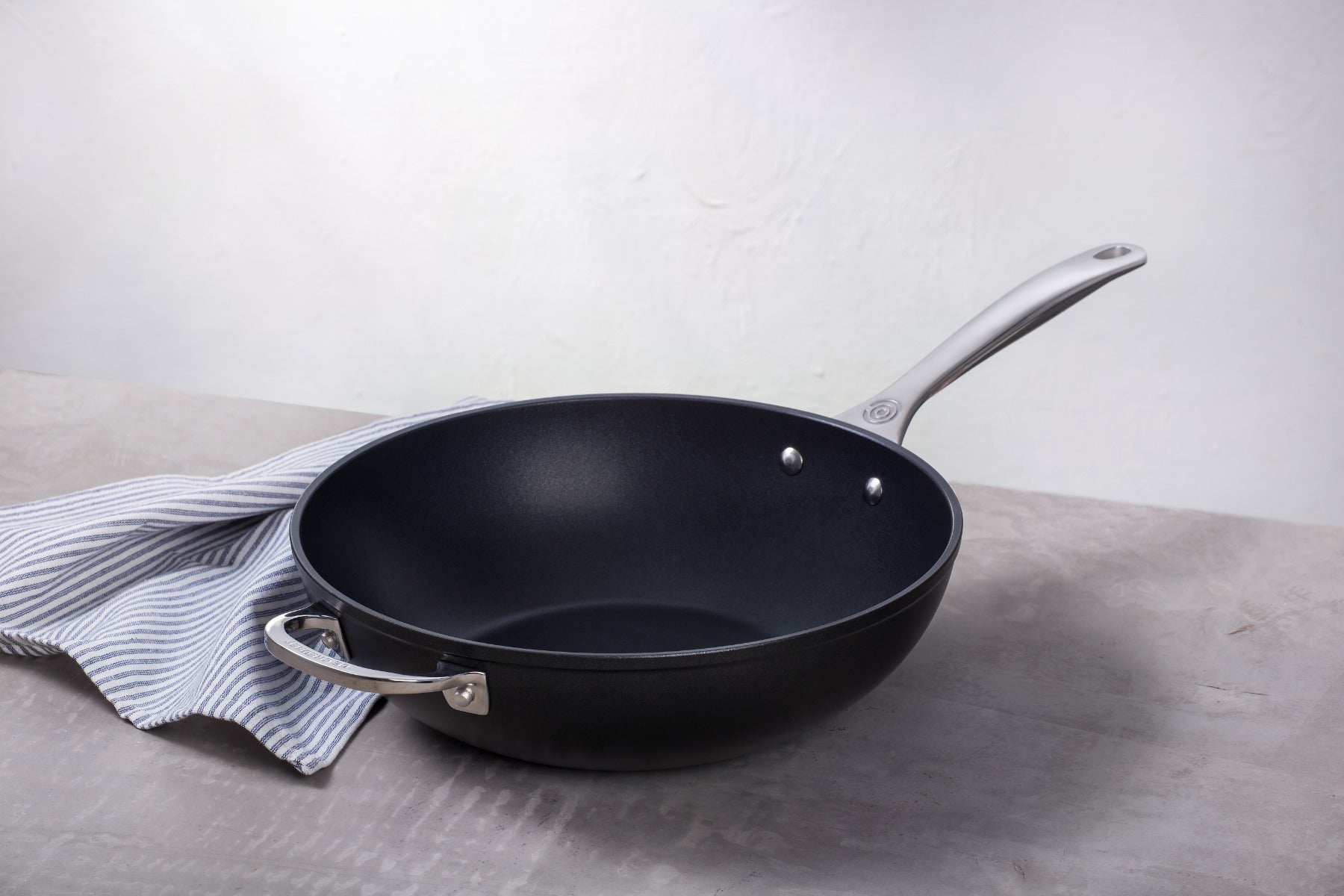 Non-stick frying pan on a striped cloth against a neutral background