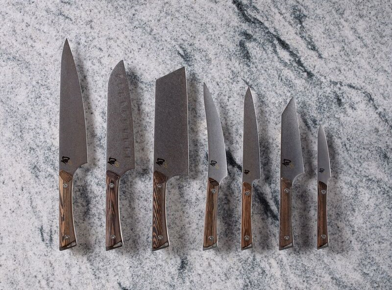 Set of seven chef knives with wooden handles on marble countertop