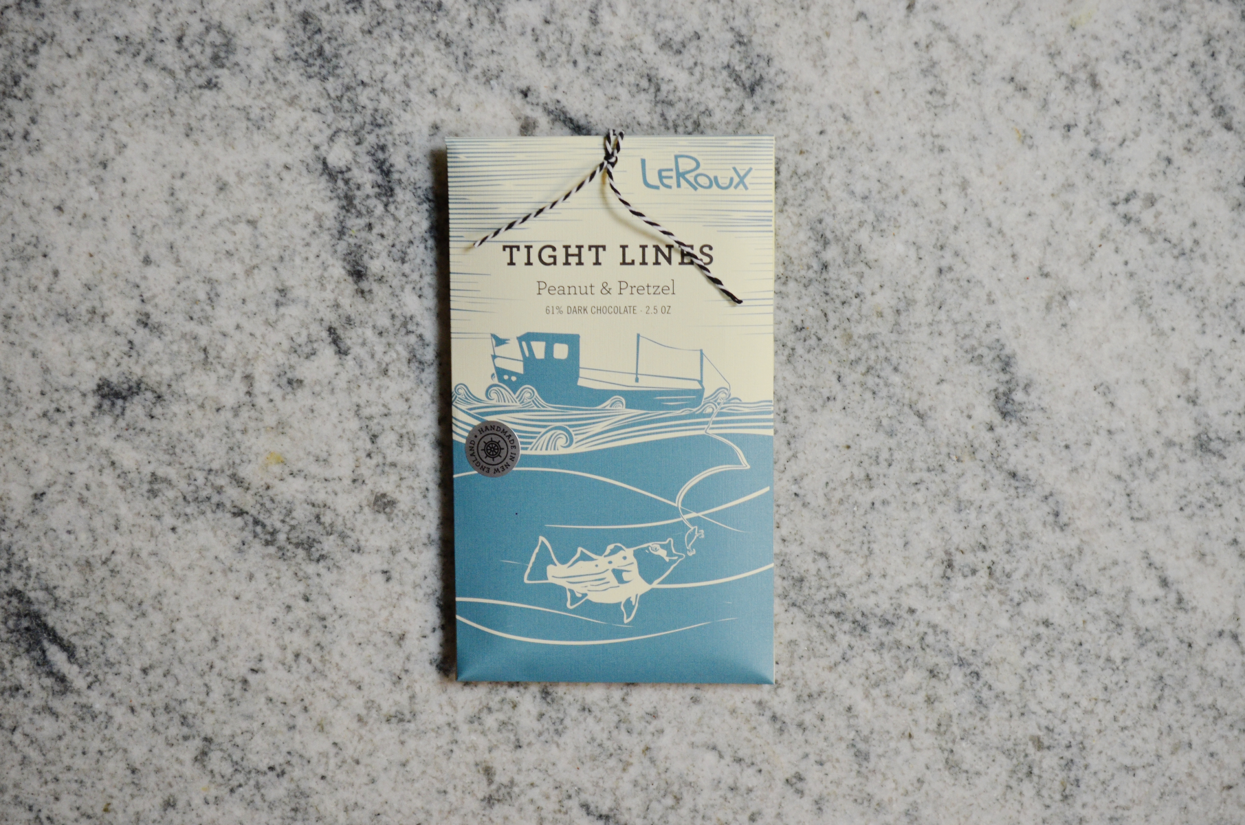 LeRoux Tight Lines peanut and pretzel dark chocolate bar on marble surface.