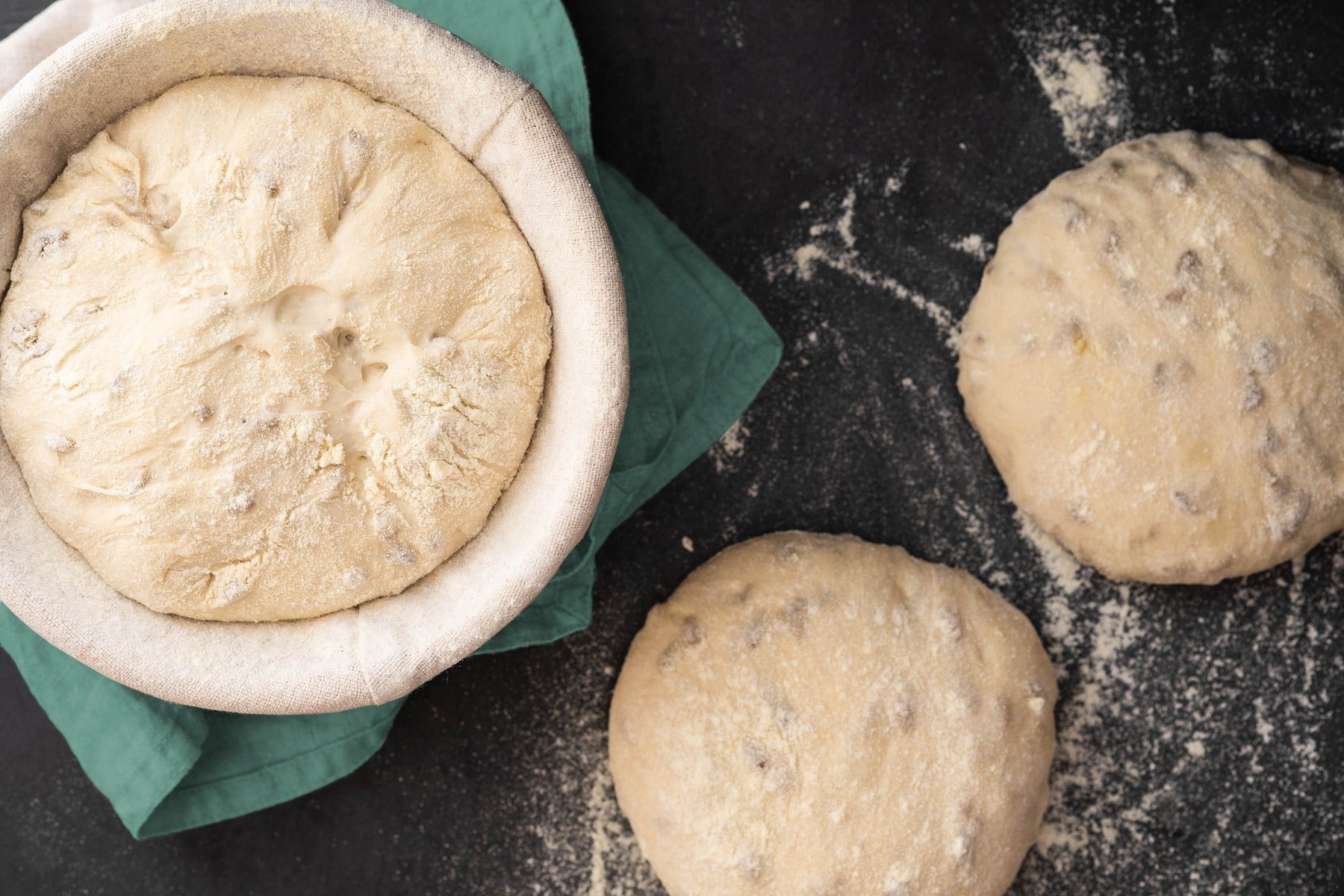 Fresh bread dough proofing in baskets on floured surface