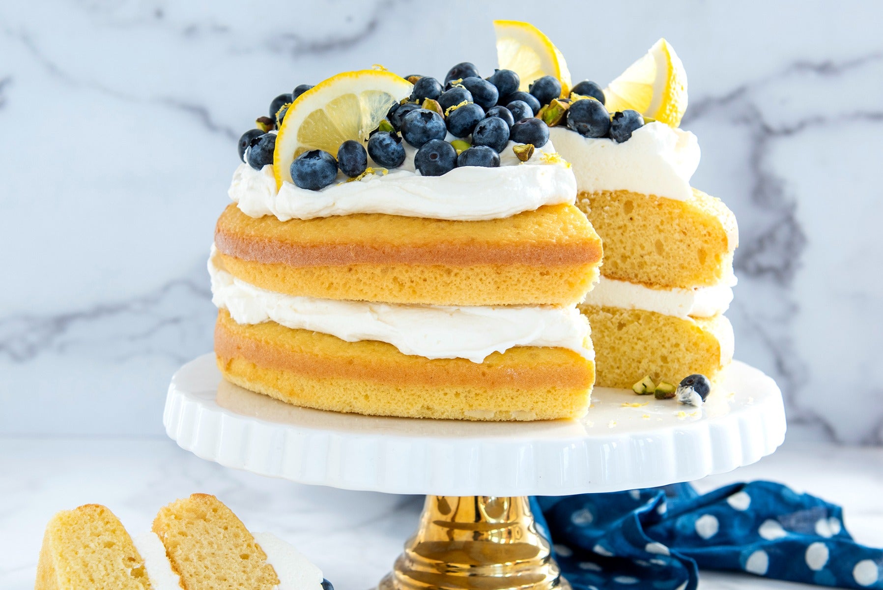 Lemon blueberry layer cake with cream on marble backdrop