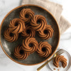Plate of chocolate swirl cupcakes on marble background with gold fork