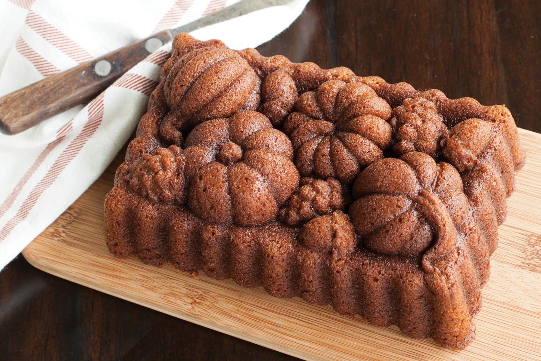 Fresh baked cinnamon swirl bread on wooden board with knife