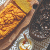 Freshly baked pumpkin-shaped pound cake beside empty bundt pan and whipped cream