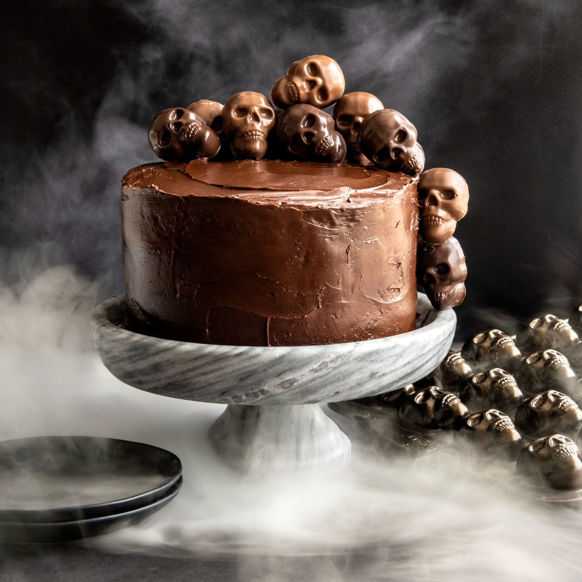 Chocolate cake with skull decorations on marble stand with misty backdrop