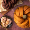 Chocolate and vanilla bundt cakes on wooden boards with sugared pastries