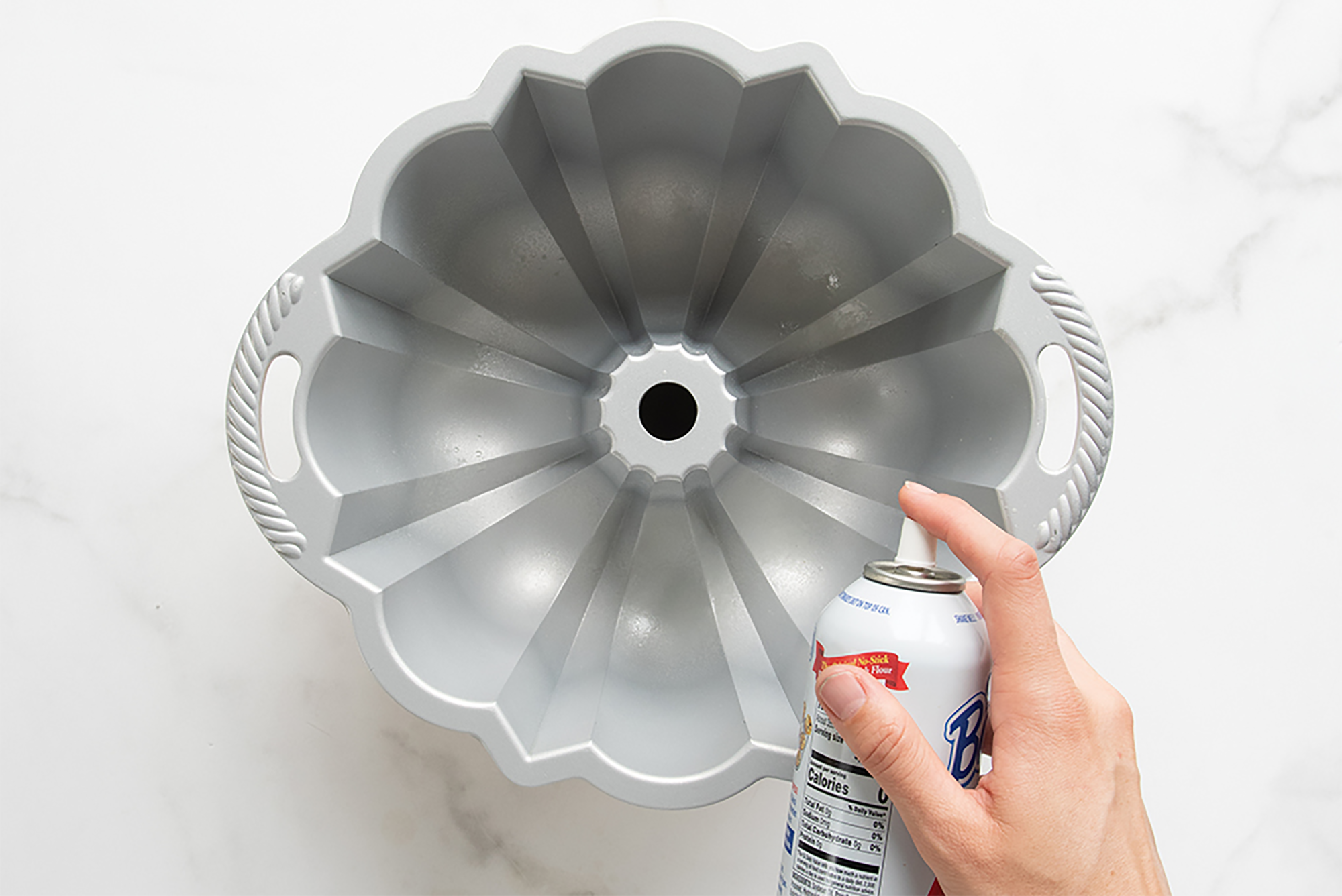 Nordic Ware Baker's Joy Non-Stick Spray is sprayed into a bundt pan.