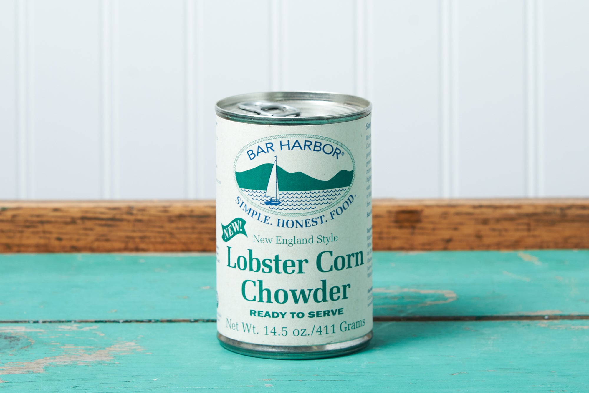 A can of Bar Harbor Foods Lobster Corn Chowder sits on a turquoise wooden table.
