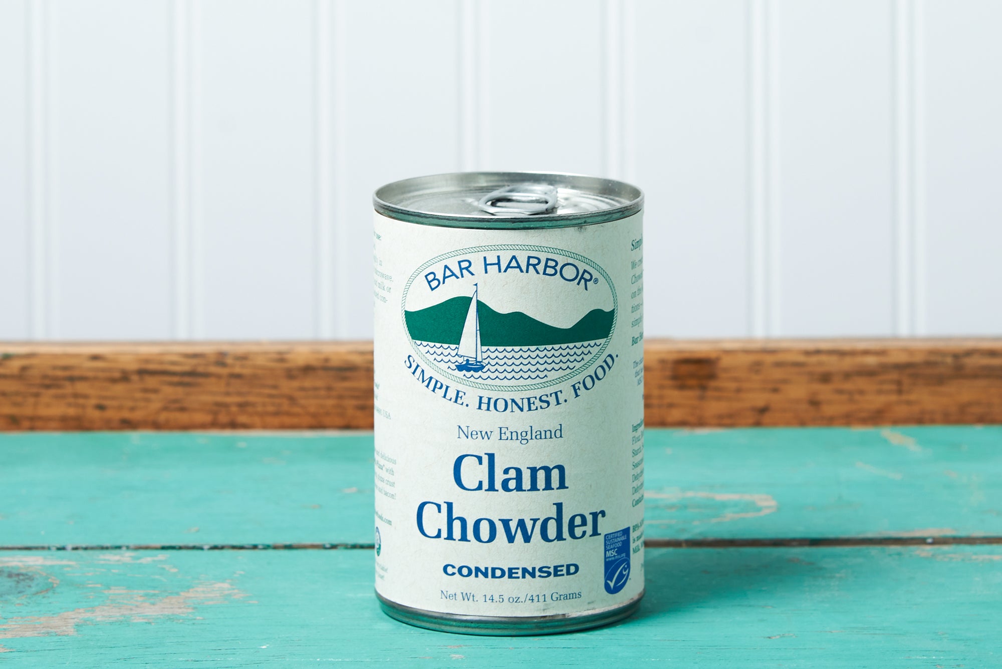 A can of Bar Harbor Foods New England Clam Chowder sits on a turquoise wooden table.