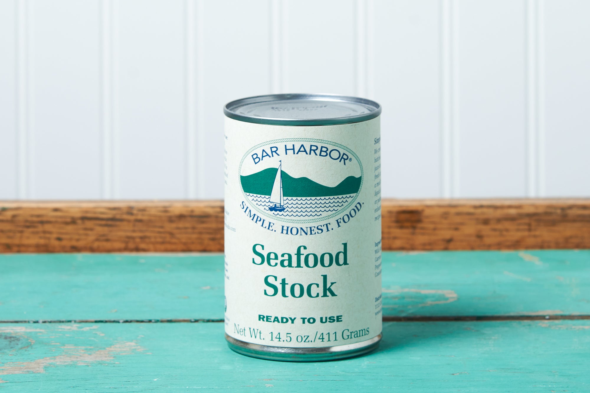 A can of Bar Harbor Foods Seafood Stock sits on a turquoise wooden table.