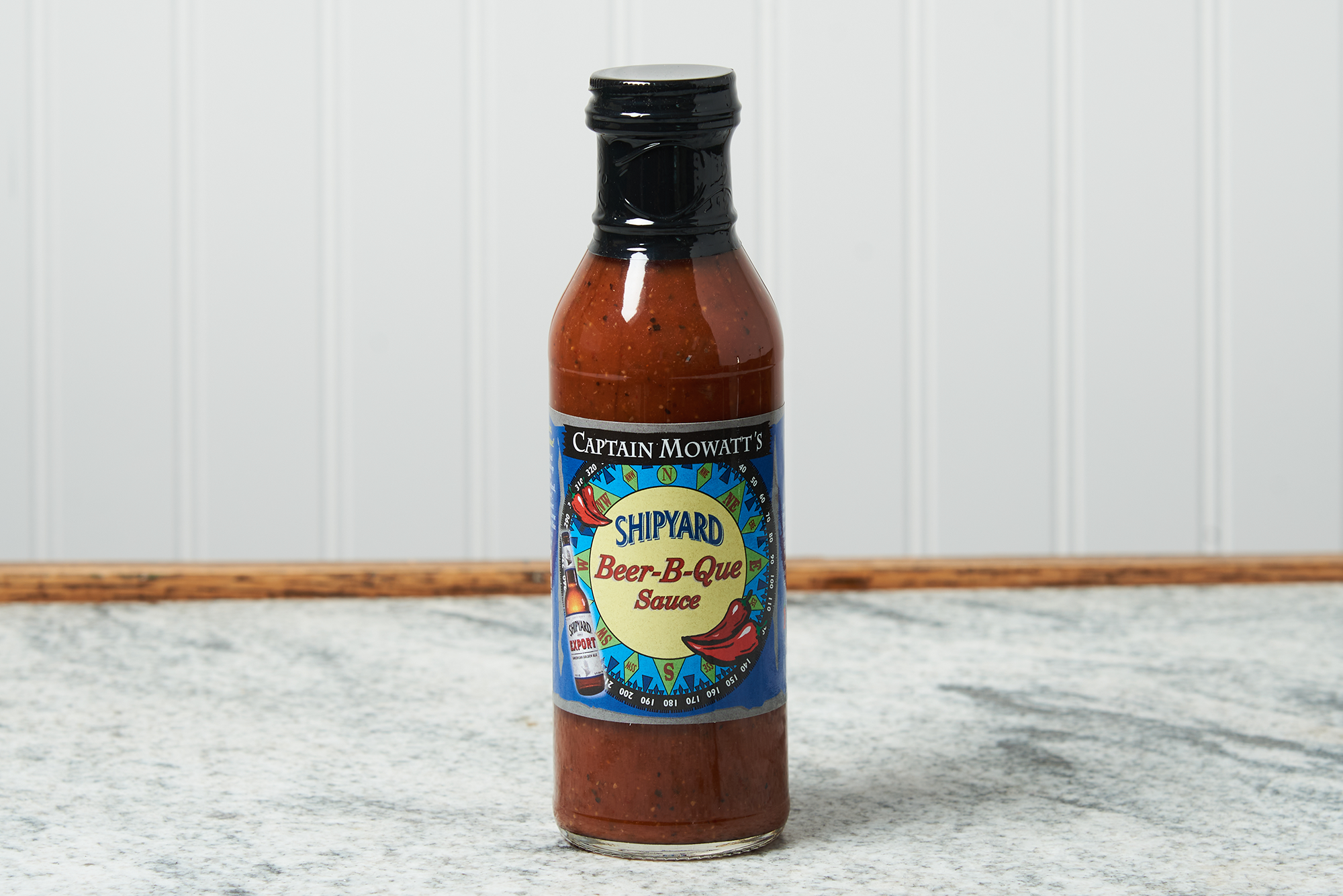 A bottle Captain Mowatt's Shipyard Beer-B-Que Sauce of sits on a marble countertop.