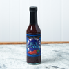 A bottle of Captain Mowatt's Blue Flame Sauce sits on a marble countertop.