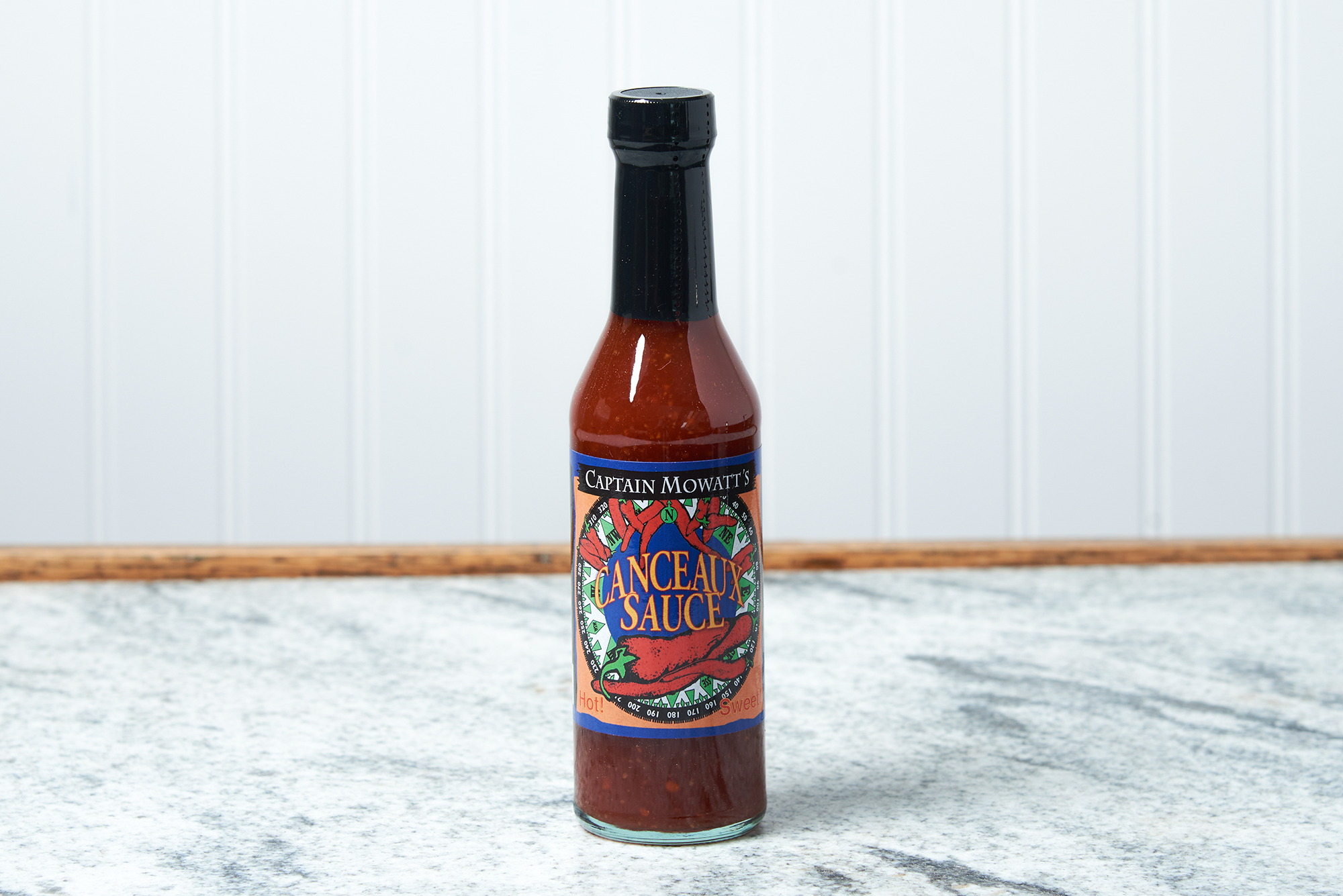 A bottle of Captain Mowatt's Canceaux Sauce sits on a marble countertop.