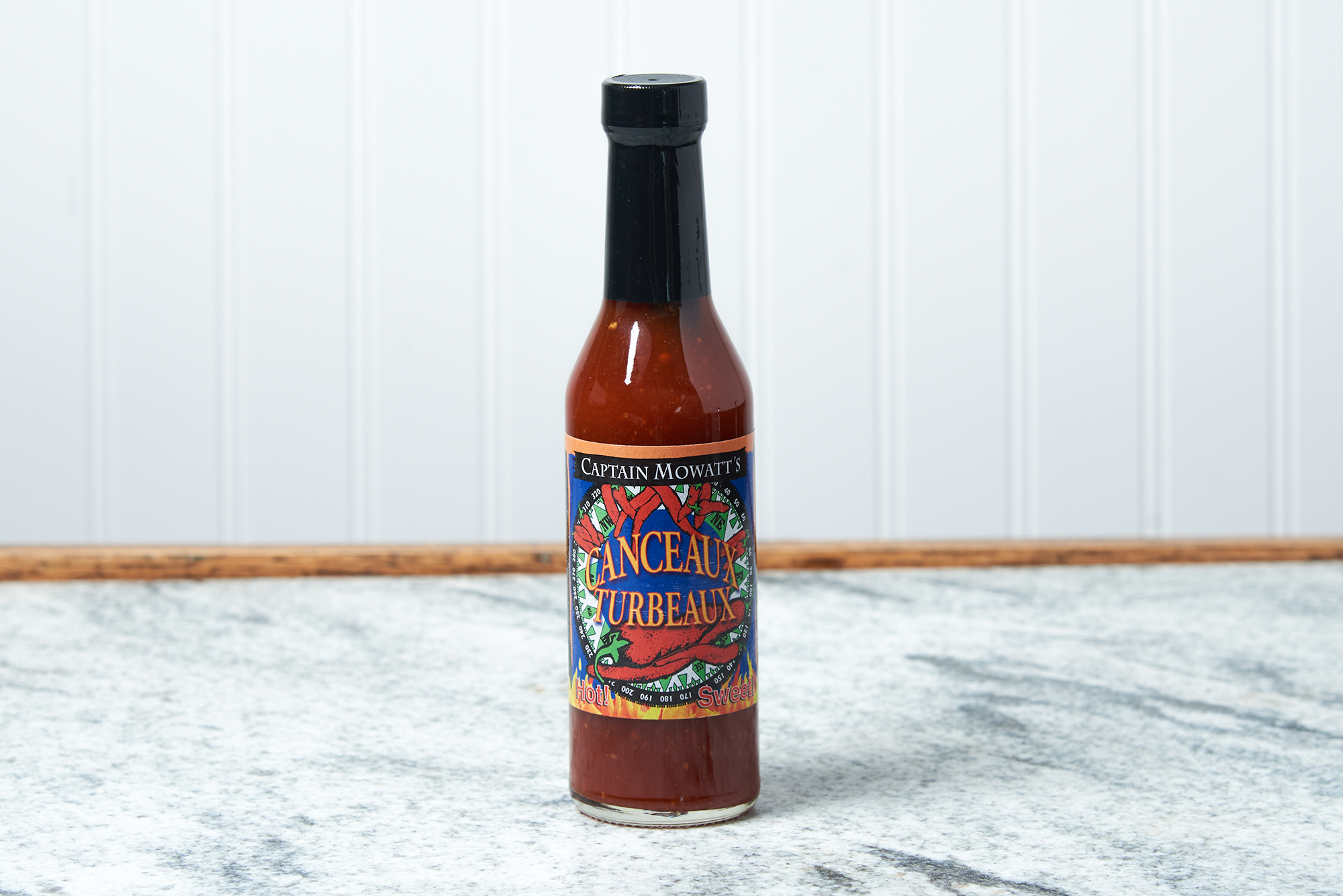 A bottle of Captain Mowatt's Canceaux Turbeaux Sauce sits on a marble countertop.