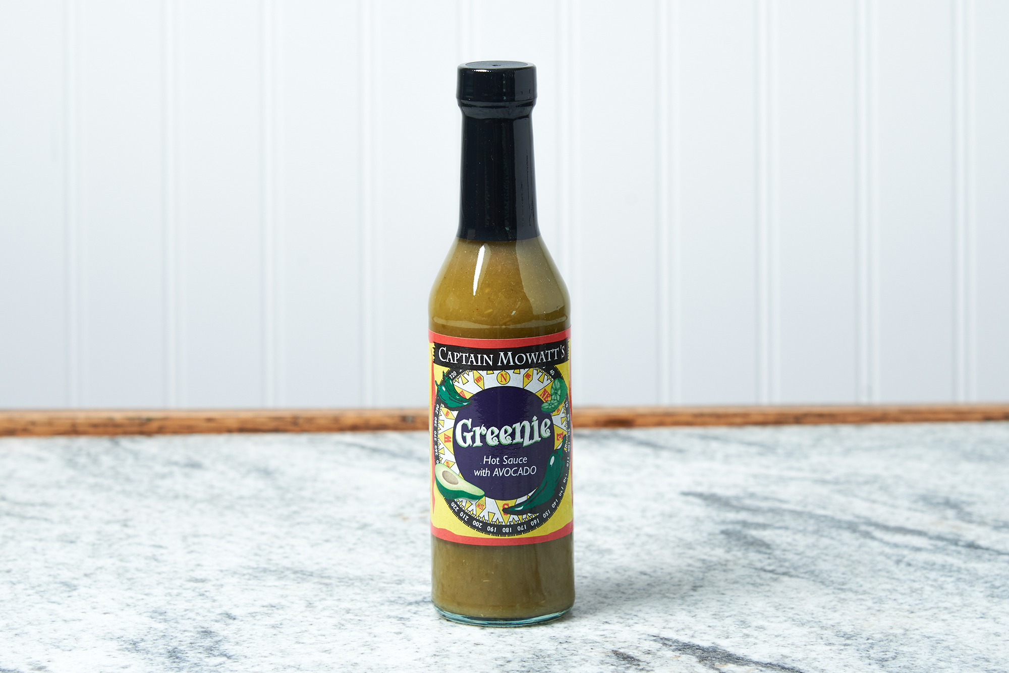 A bottle of Captain Mowatt's Greenie Sauce sits on a marble countertop.