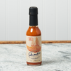 A bottle of Chad's Code Zero - No Heat Hot Sauce sits on a marble countertop.