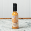 A bottle of Chad's Double Reef Hot Sauce sits on a marble countertop.