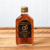 A bottle of Cobb's Hill Hitched Maple Syrup sits on a brown wooden table.