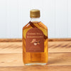 A bottle of Cobb's Hill Sugar and Spice Maple Syrup sits on a brown wooden table.