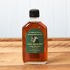 A bottle of Cobb's Hill Tipsy Hoot Owl Maple Syrup sits on a brown wooden table.