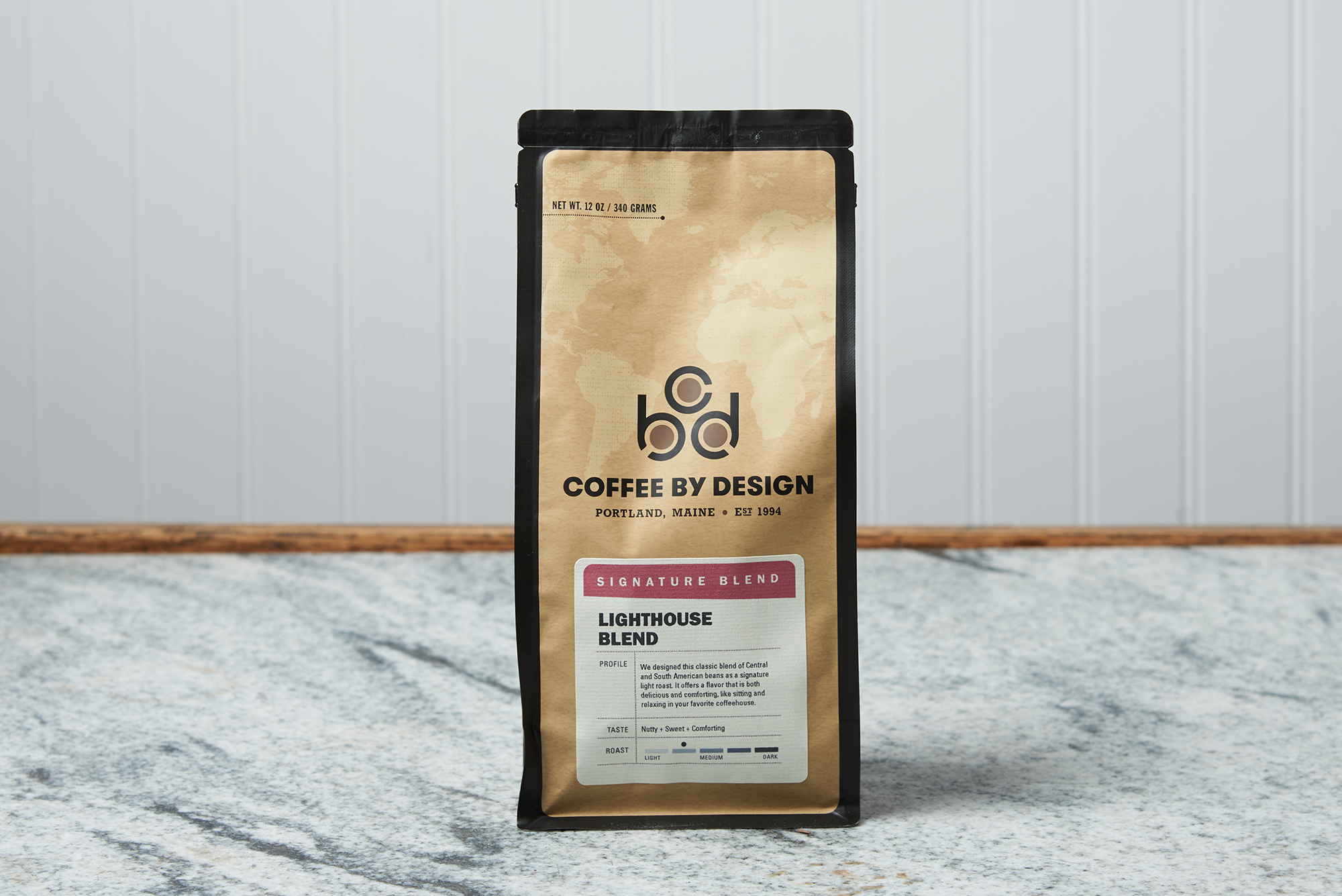 A bag of Coffee By Design Lighthouse Blend coffee sits on a marble countertop.